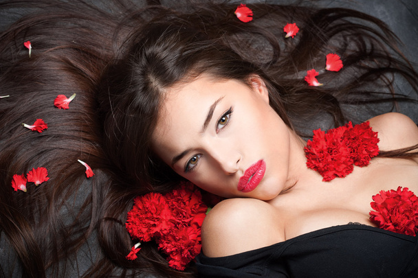 Woman with long hair and red carnations - Fotoğraf, Görsel