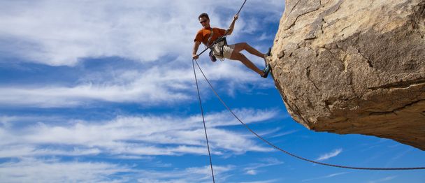 mannelijke rock klimmer abseilen. - Foto, afbeelding