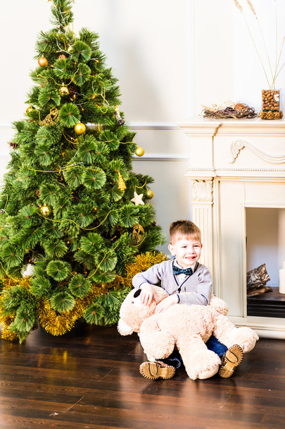 Porträt eines süßen Jungen mit Teddybär am Weihnachtsbaum - Foto, Bild
