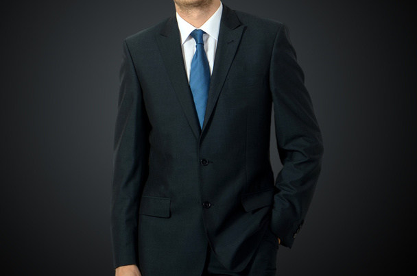 Nahaufnahme eines Geschäftsmannes im Anzug vor dunkelgrauem Hintergrund - Foto, Bild