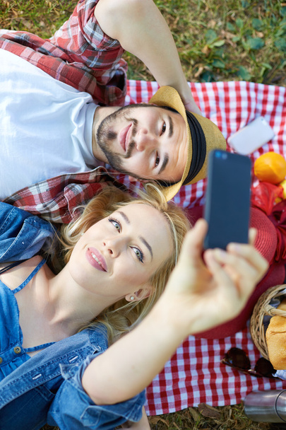 Composite of Couple taking selfie on smartphone on romantic picnic - Фото, зображення