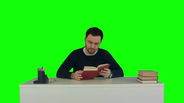 Young and concentrated student reads a book on a Green Screen - Video