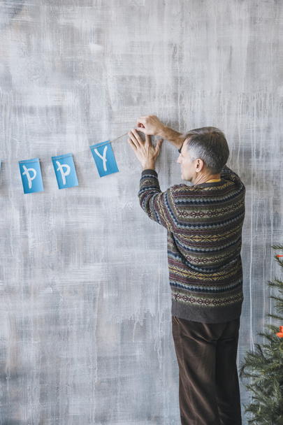 Man decorating wall with blue and white garland - Foto, immagini