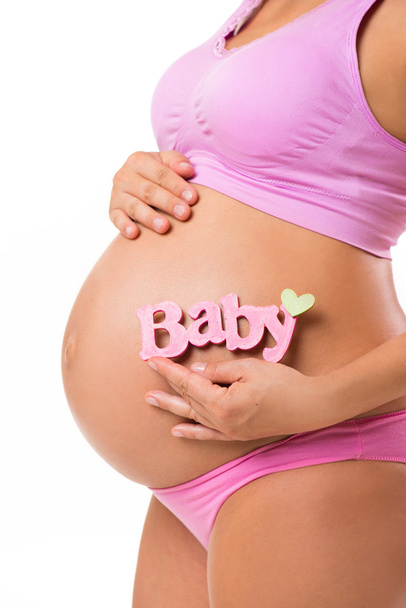 Vertical close-up of a pregnant belly with pink sign for baby girl. Determine the sex of the baby during pregnancy. - Φωτογραφία, εικόνα