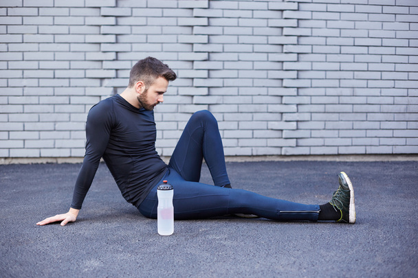 Sport man with beard stretching against concrete wall - Photo, image