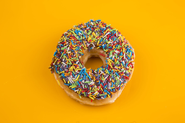 Donut con salpicaduras sobre fondo amarillo
 - Foto, imagen