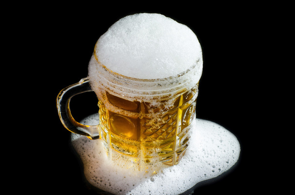 Beer mug with froth close-up over black background. - Foto, afbeelding