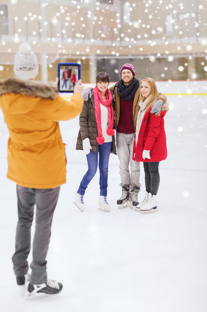 happy friends taking photo on skating rink - 写真・画像