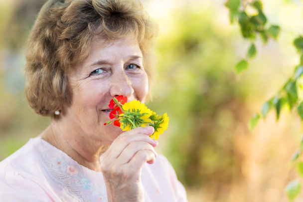 Happy elderly woman with flowers - Foto, Imagen