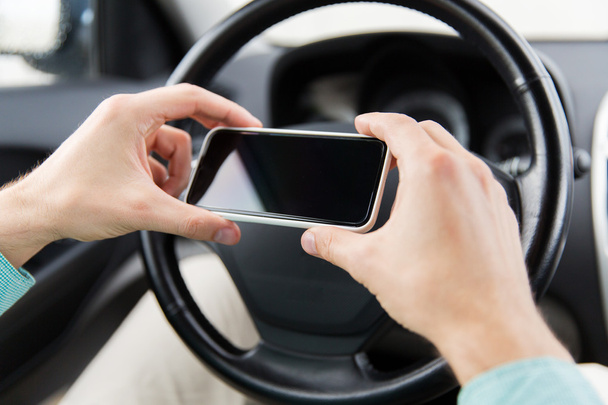 close up of man hand with smartphone driving car - Valokuva, kuva