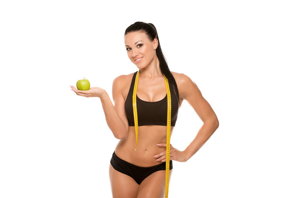 Beautiful fitness model with apple and measuring tape - 写真・画像