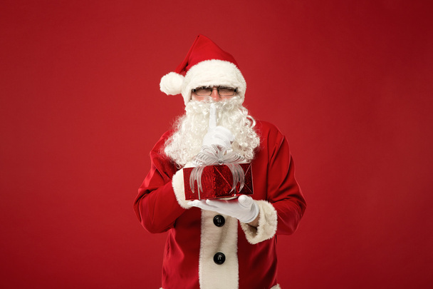 Santa Claus with a gift on a red background - 写真・画像