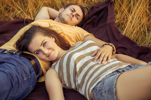 Loving couple lying down on floral field in autumnal park, warm sunny day, enjoying family, romantic date, happiness and love concept. looking at camera with smile. - Fotó, kép