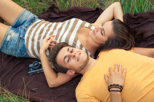 Loving couple lying down on floral field in autumnal park. enjoy, relax and r - Foto, imagen