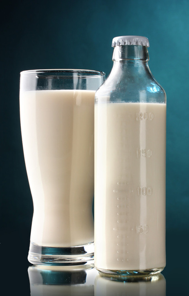 Bottle and glass of milk on blue background - Valokuva, kuva