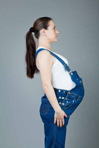 Portrait of pregnant brunette woman on grey background. - Fotoğraf, Görsel