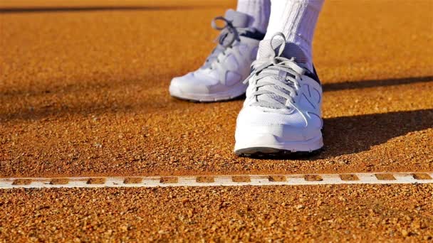 Zeitlupe eines Tennisspielers, der auf einem roten Tennisplatz vor dem Servieren einen Tennisball hüpft - Filmmaterial, Video