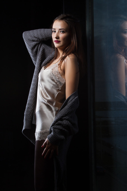 Girl standing near a window in a dark room - Fotografie, Obrázek
