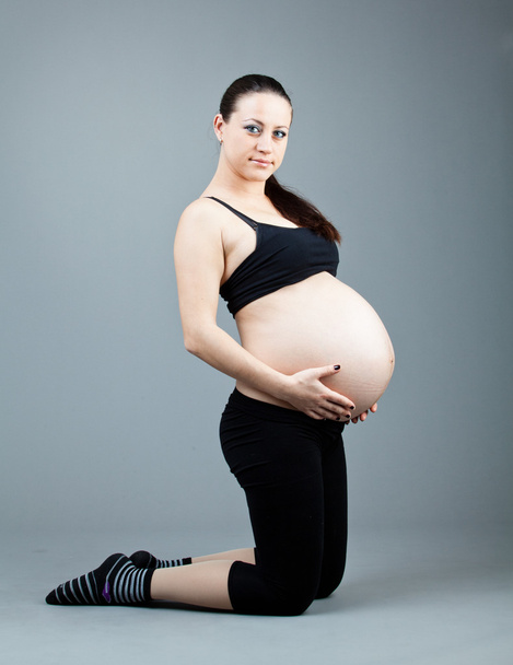 Portrait of pregnant brunette woman on grey background. - Photo, image
