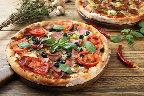 Pizza mit Schinken-Tomatenscheibe und Paprika auf rustikalem Holztisch - Foto, Bild