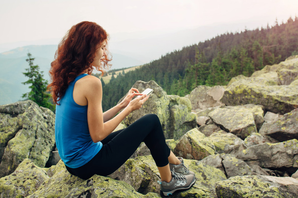 Nainen käyttää älypuhelinta vuorilla
 - Valokuva, kuva