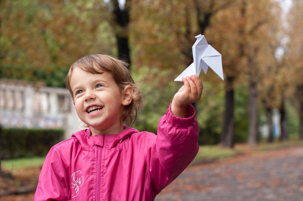 Little girl holding a paper dove - Фото, изображение