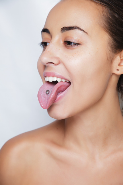 schöne Frau streckt ihre Zunge heraus und zeigt junge Piercings - Foto, Bild