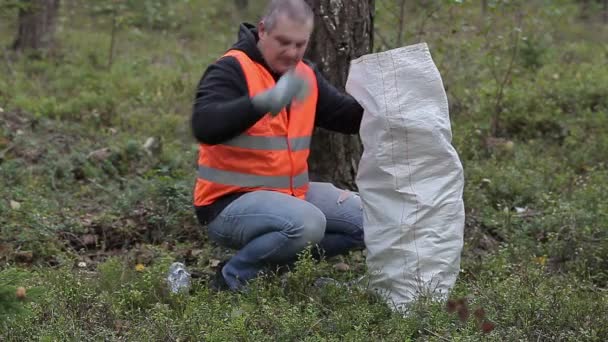 Mann mit Tasche sammelt gebrauchte Plastikflaschen ein - Filmmaterial, Video