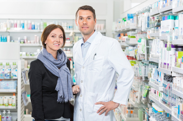 Confident Pharmacist Standing With Customer In Pharmacy - Foto, Imagen