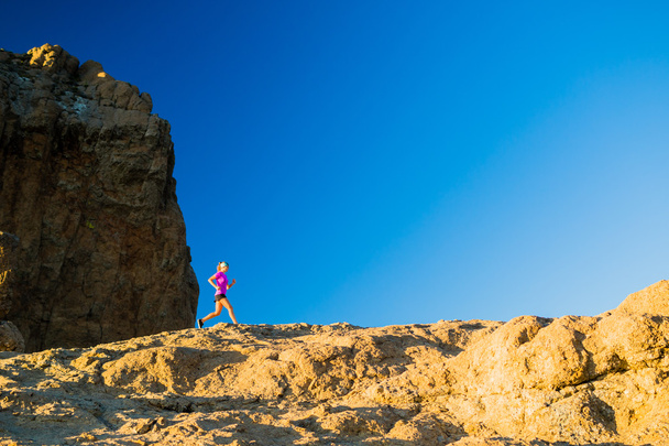 Woman trail running on rocky mountains - Foto, afbeelding