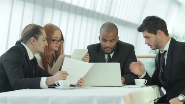 Cuatro exitosos hombres de negocios sonrientes sentados a la mesa en la oficina
 - Metraje, vídeo