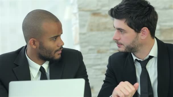 Dva mladí muži diskutují o informacích na obrazovce přenosného počítače - Záběry, video