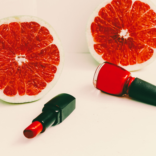 Red accent. Lipstick, nail polish, and grapefruits. minimal phot - 写真・画像