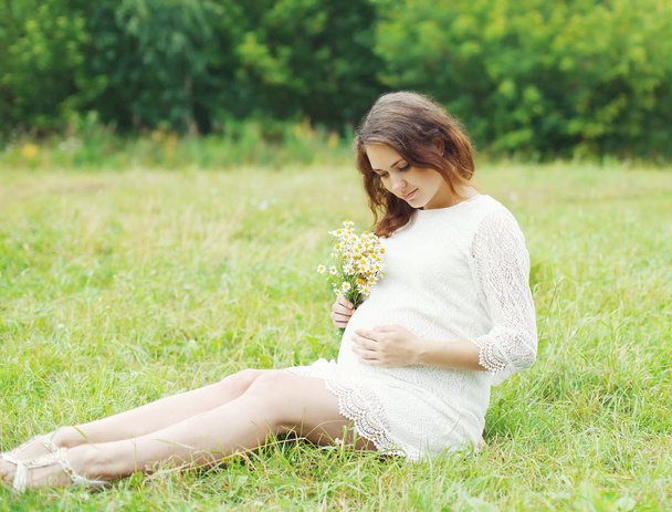 Kaunis nuori raskaana oleva nainen kamomilla kukkia makaa
 - Valokuva, kuva