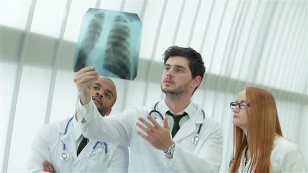 Tres médicos confiados examinando radiografía de los pulmones en el hospital
 - Metraje, vídeo