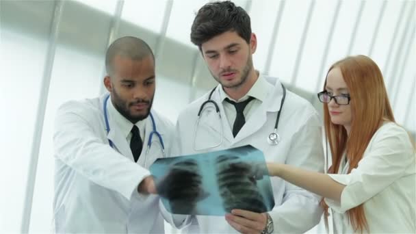 Tre medici fiduciosi che esaminano l'istantanea a raggi X dei polmoni in ospedale
 - Filmati, video
