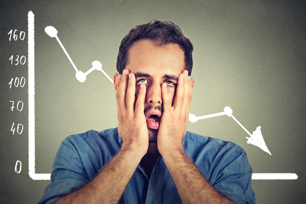 frustrated stressed young man desperate with financial market chart graphic going down - 写真・画像