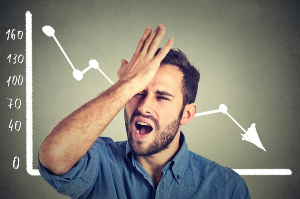 frustrated stressed young man desperate with financial market chart graphic going down - 写真・画像