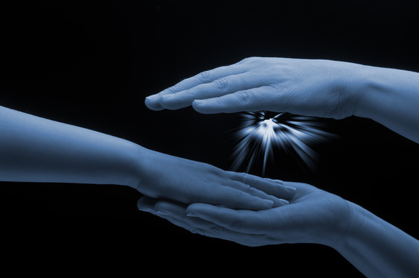 Mother hands holding child hand. Spark of hope in a woman hand on dark background. The light of faith. - Foto, Bild