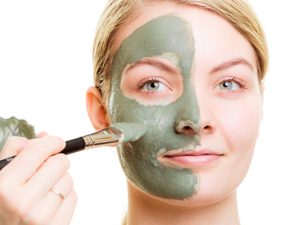 Cosmetician applying clay facial mask at woman face. - Foto, imagen