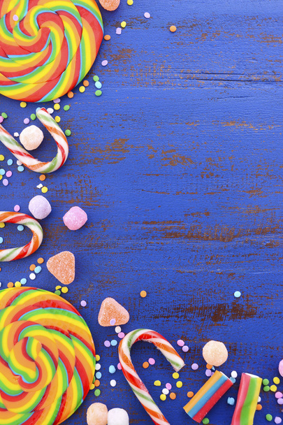 Dulces de piruleta de arco iris brillante en mesa de madera azul oscuro
. - Foto, imagen