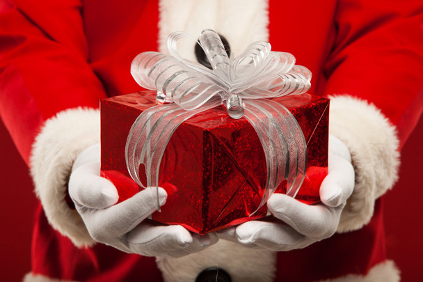 Photo of kind Santa Claus giving xmas present and looking at camera. - Foto, afbeelding