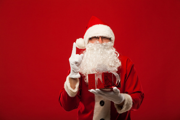 Photo of kind Santa Claus giving xmas present and looking at camera. - Foto, Imagem