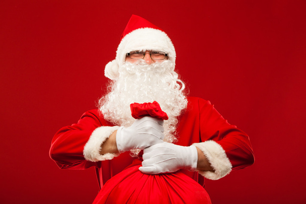 santa claus with big bag on shoulder glasses  red background - Foto, immagini