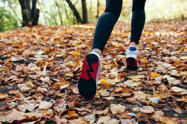 woman runs for fall foliage, shoes closeup - Foto, afbeelding