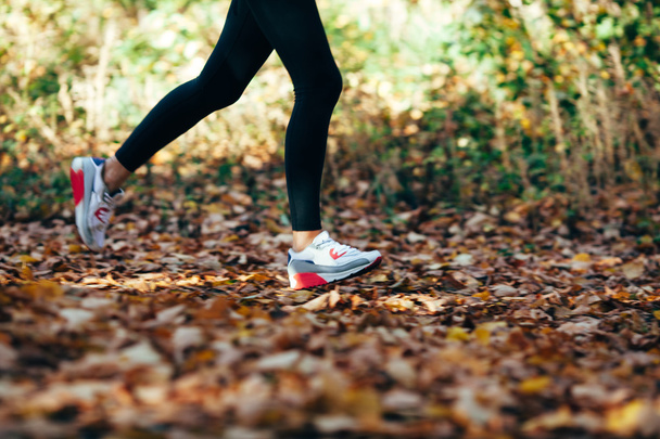жінка біжить на осіннє листя, взуття крупним планом, розмивання руху
 - Фото, зображення