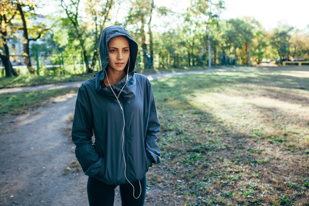 sporty woman wearing hood jacket and listening music - Foto, imagen