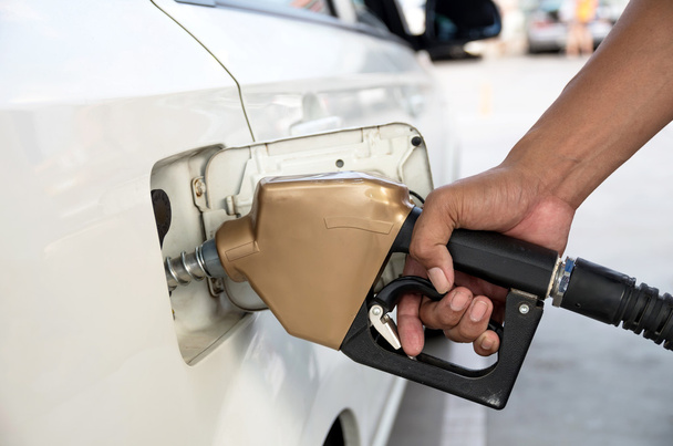 Mannen houden brandstof mondstuk om toe te voegen van brandstof in auto op tankstation - Foto, afbeelding