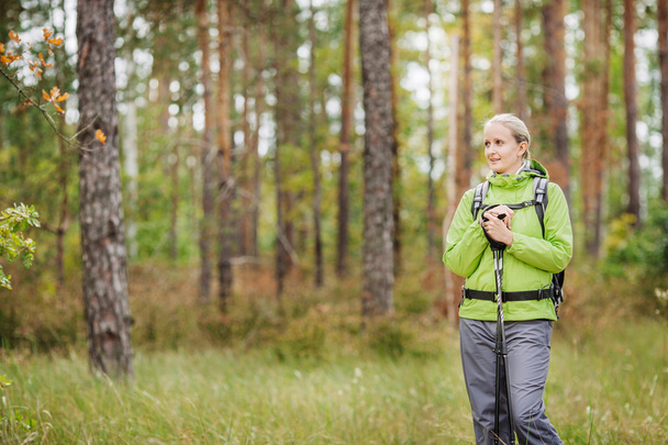 woman with hiking equipment walking in forest - Foto, Imagem