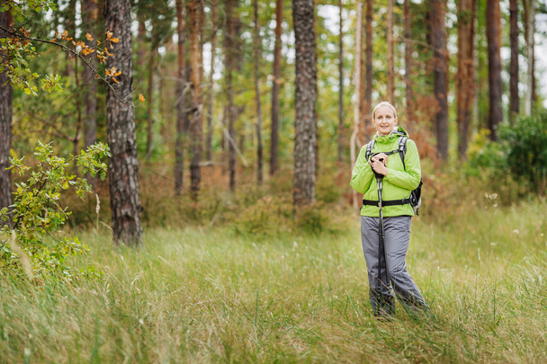 woman with hiking equipment walking in forest - Foto, Bild